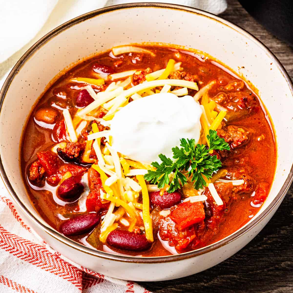 A bowl of smoked chili served with shredded cheese and sour cream.