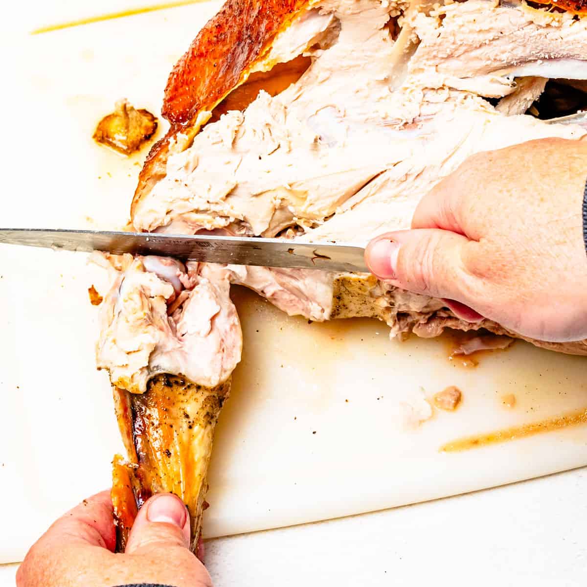 Cutting the wing drum from a roasted turkey.