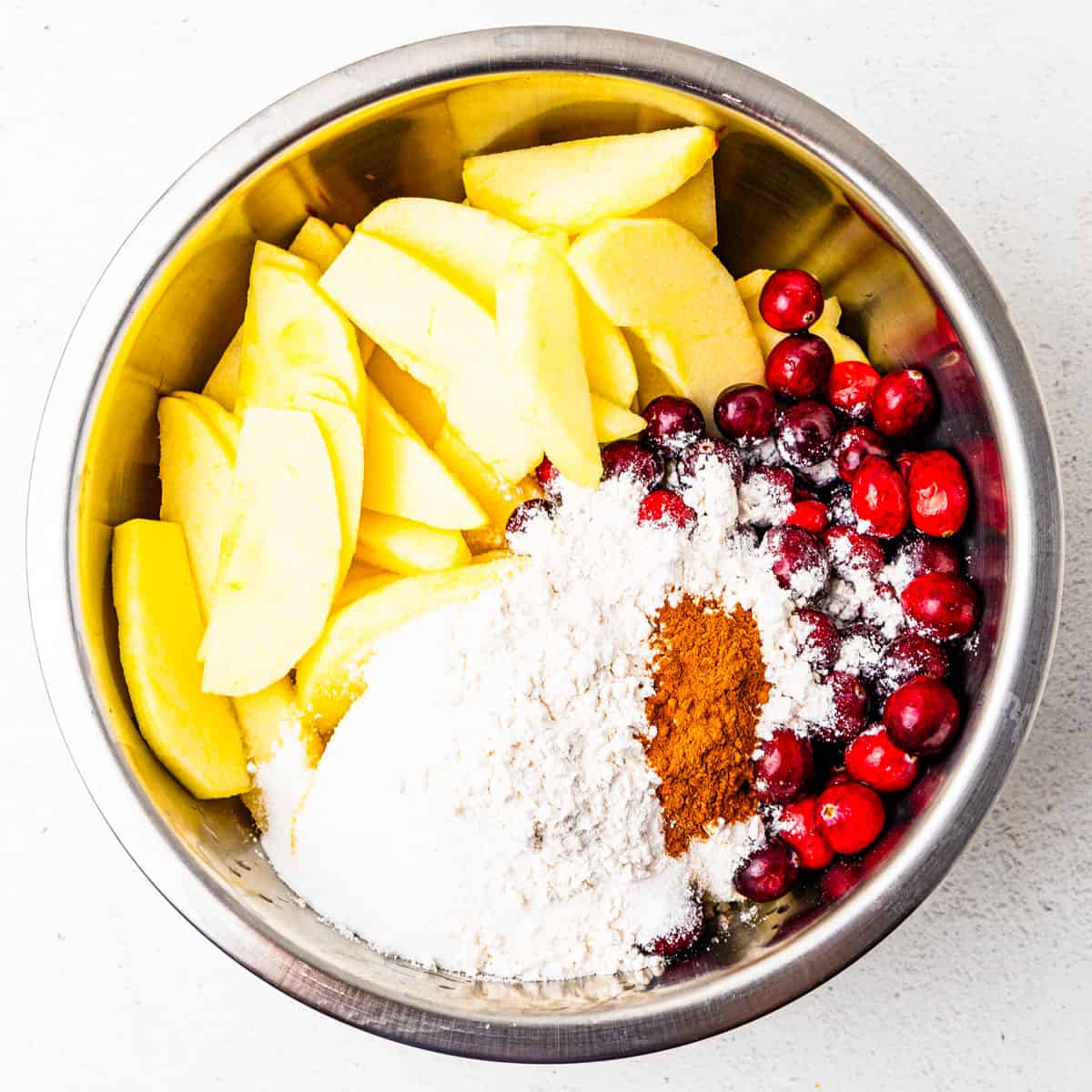 Ingredients for cranberry apple crisp filling in a mixing bowl before being mixed together. 