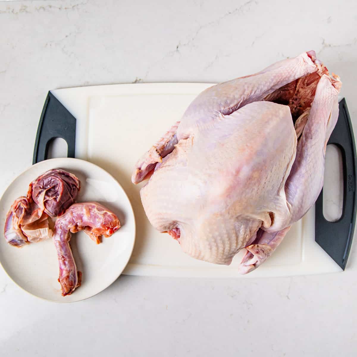 A turkey with the neck and giblets removed and sitting on a plate.