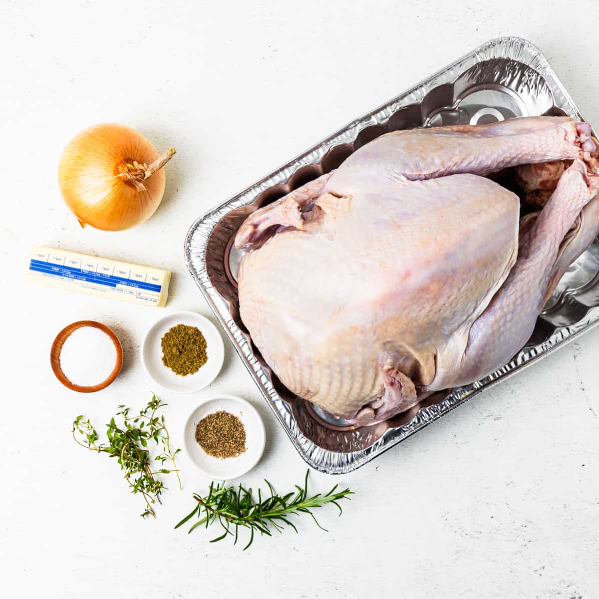 An turkey and ingredients for roasted turkey sitting on a counter.