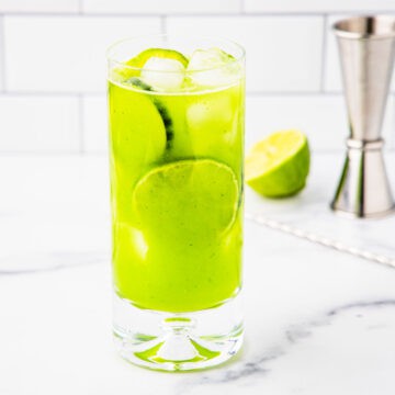 A cucumber mocktail drink in a tall glass.