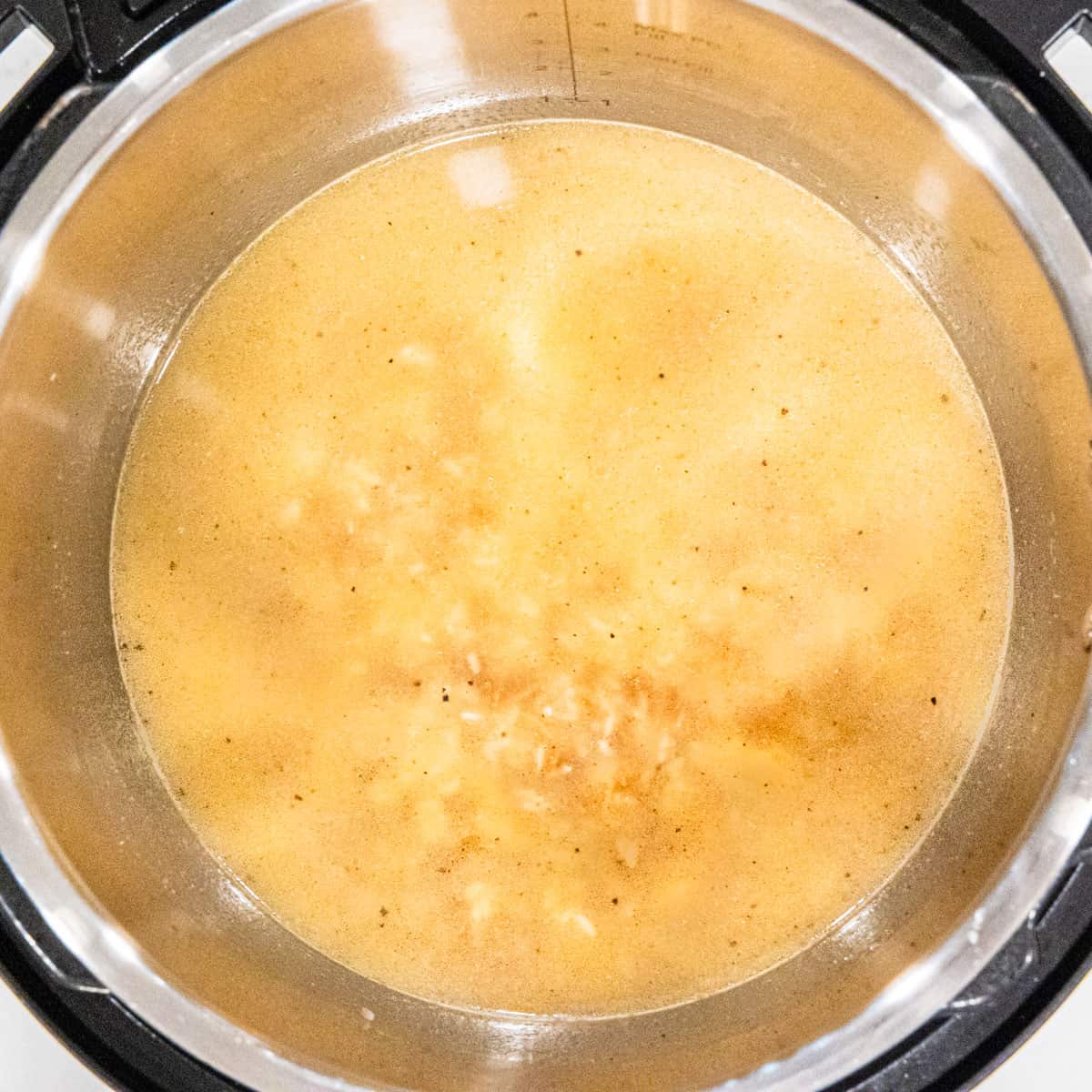 Chicken broth and rice in an Instant Pot before cooking the rice.