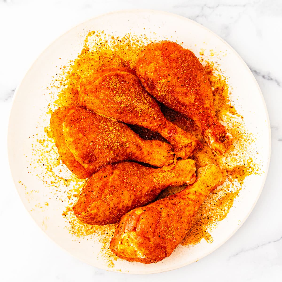 A plate of chicken legs seasoned with barbecue rub seasoning. 