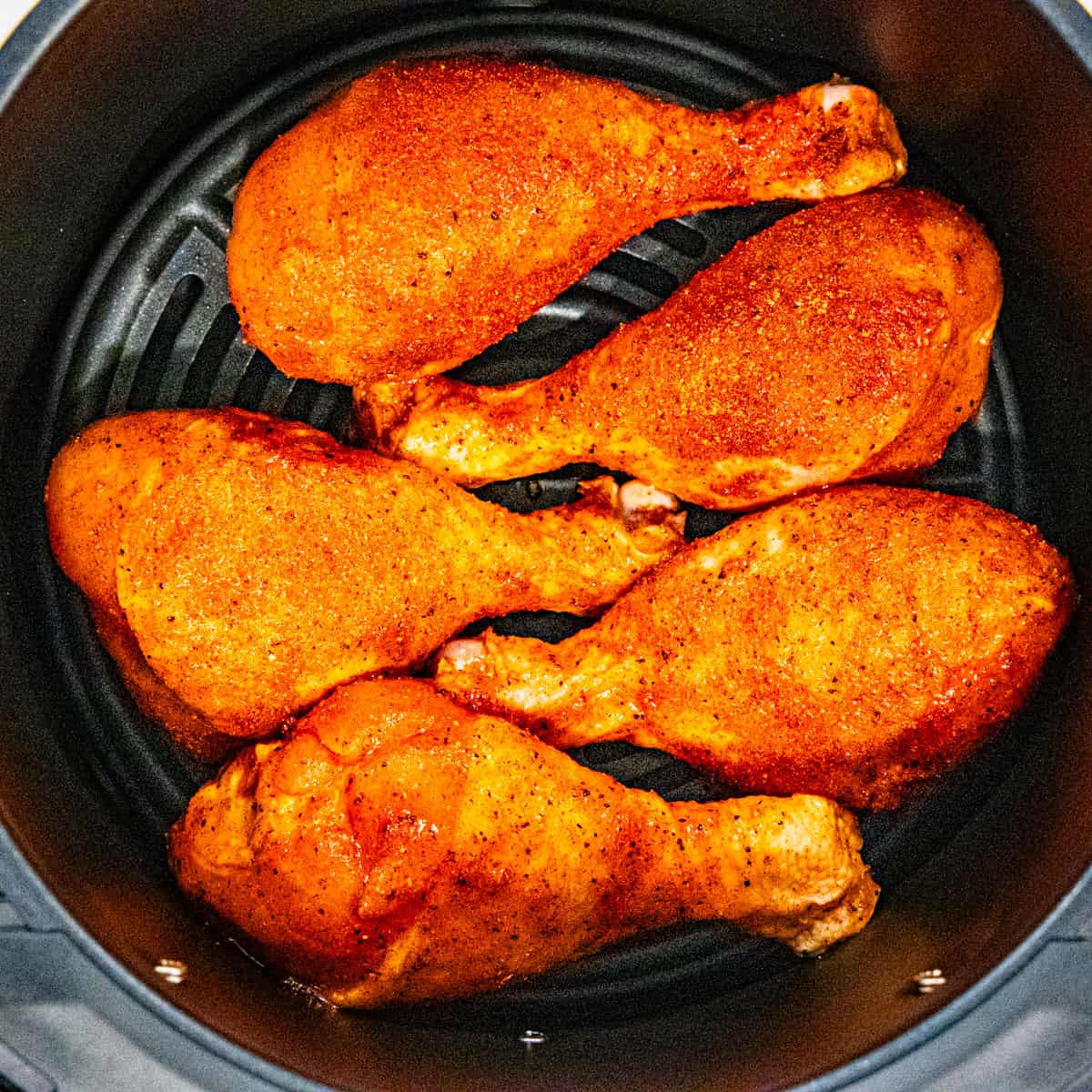 Chicken legs in an air fryer before cooking.