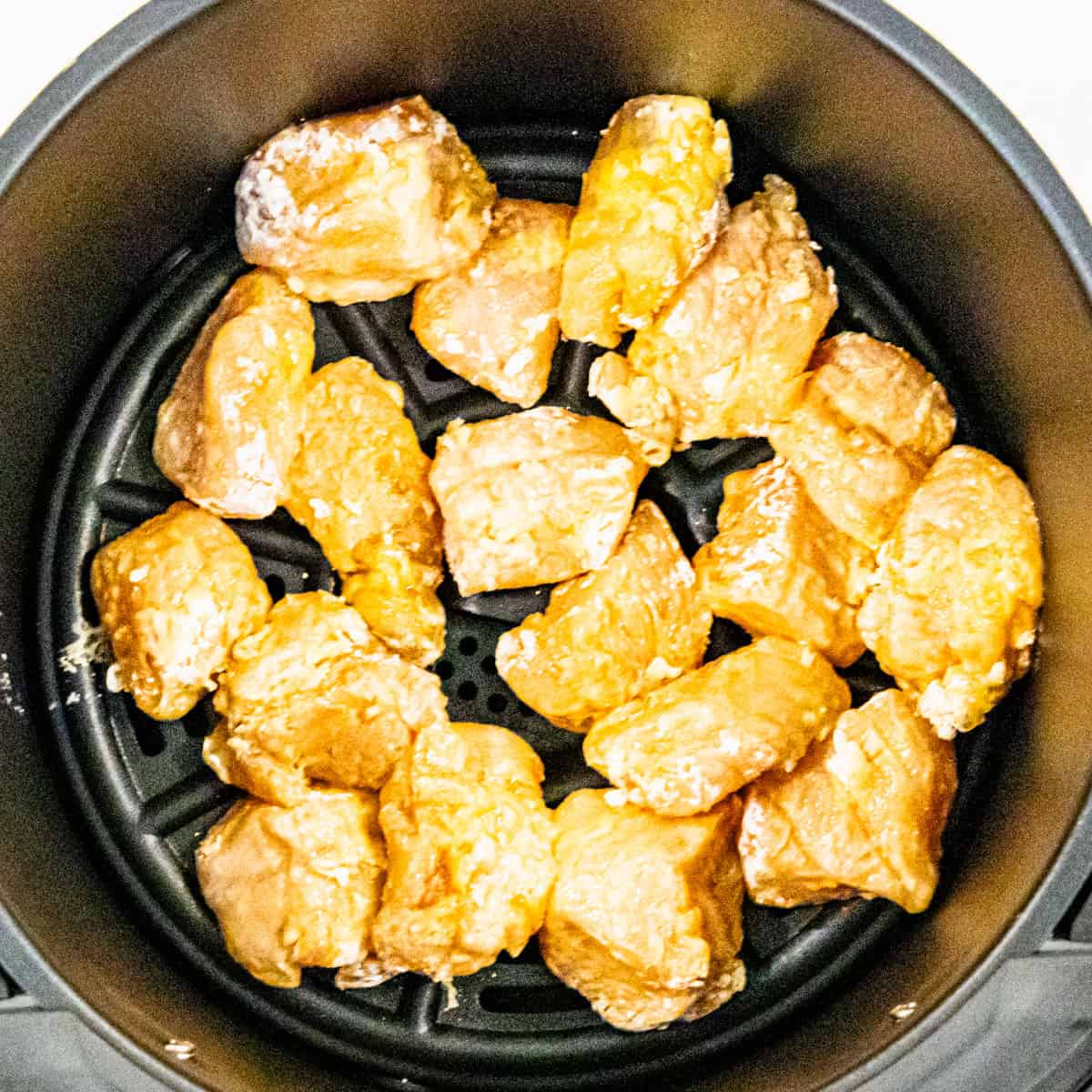 Chicken pieces in an air fryer basket.