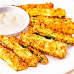 A plate of zucchini fries served with dipping sauce.