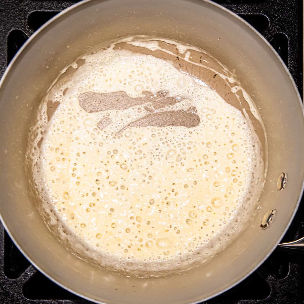 A roux of butter and flour cooking in a pot.