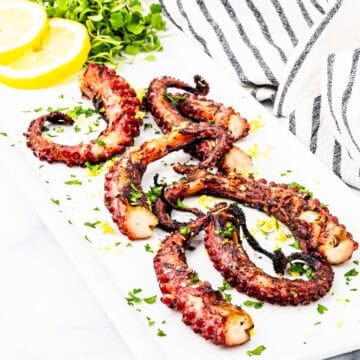 Grilled octopus legs on a platter.