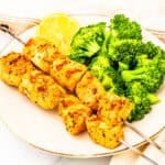 A plate of salmon kabobs served with broccoli.