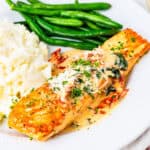 A pan-seared salmon filet, topped with a cream sauce with spinach and sundried tomatoes.