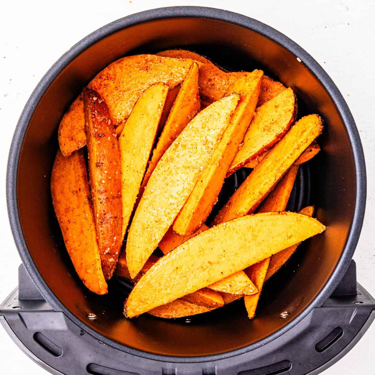 Sweet potatoes in an air fryer basket before cooking. 