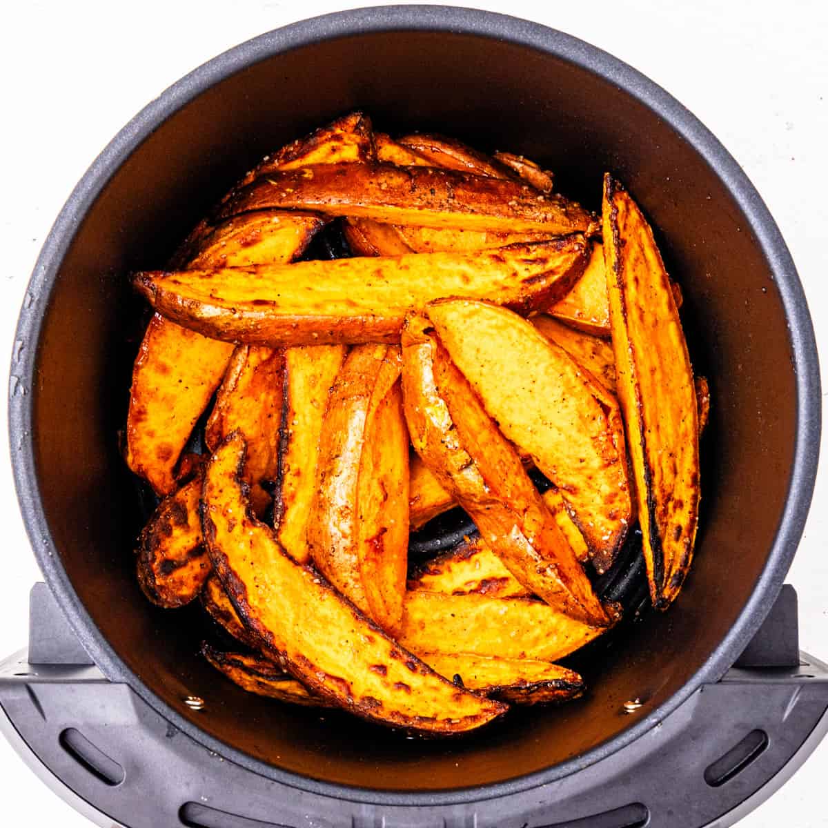 Sweet potatoes in an air fryer basket after cooking. 