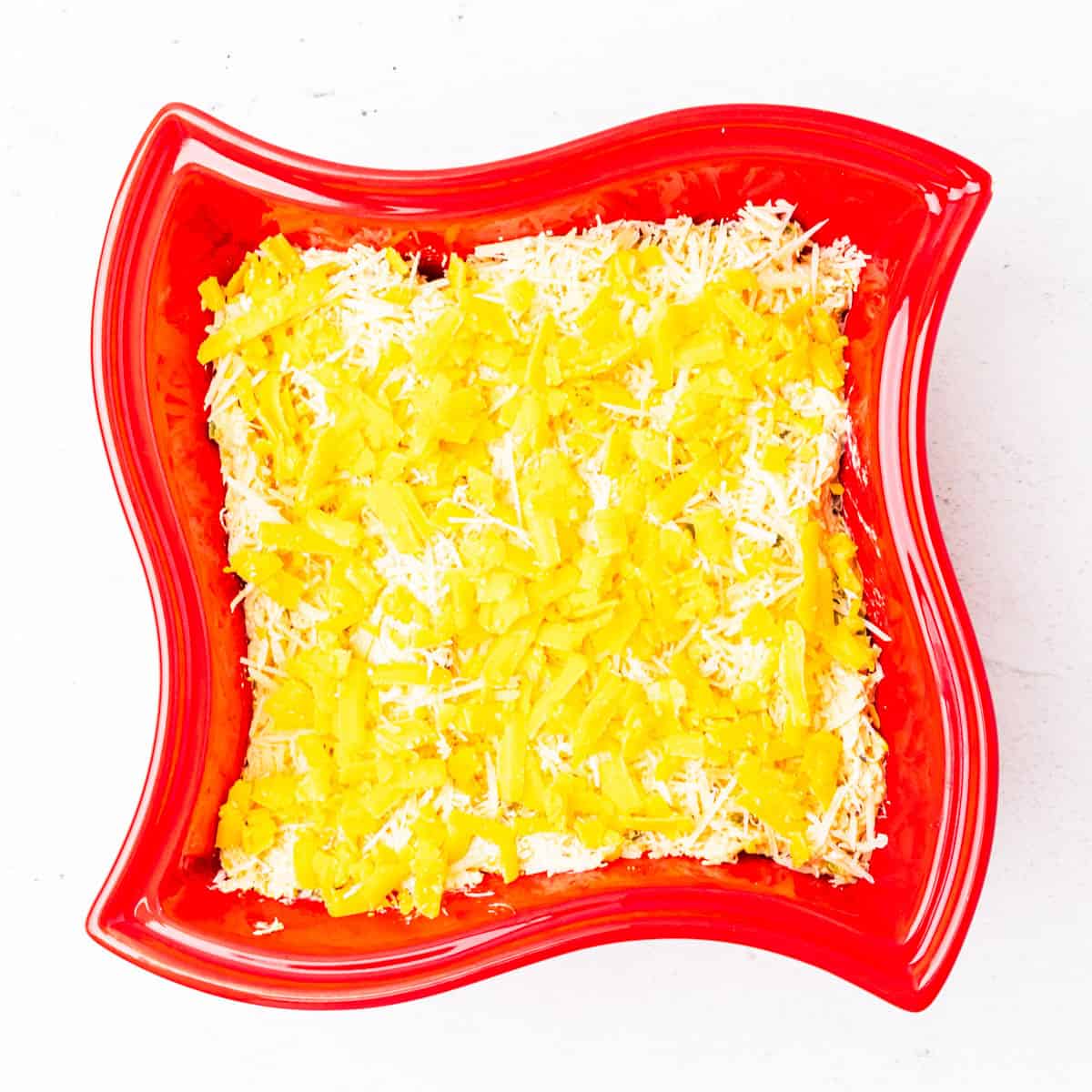 Unbaked crab dip topped with cheddar cheese.