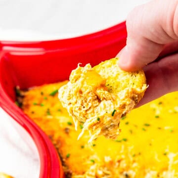 Cajun crab dip being scooped with a tortilla chip.