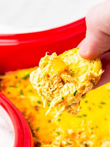 Cajun crab dip being scooped with a tortilla chip.