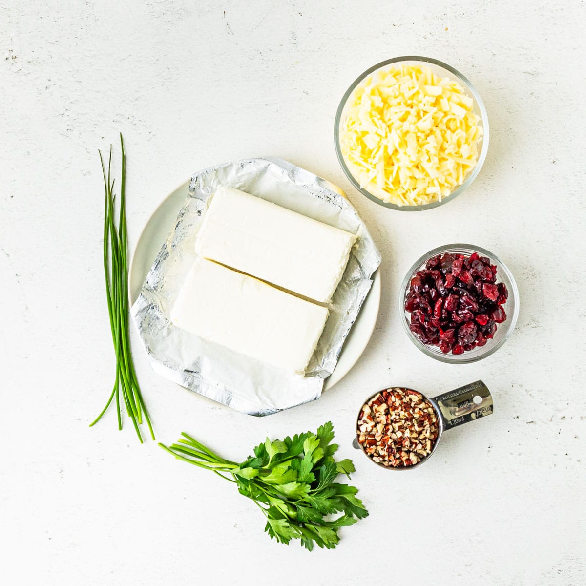 Ingredients for cranberry pecan cheese ball arranged on a countertop.