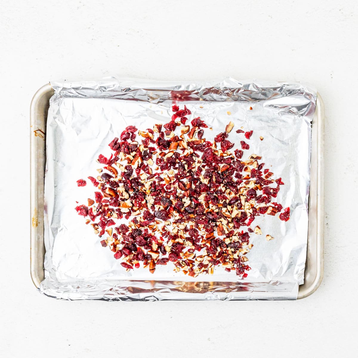 Cranberry pecan coating scattered on a sheet pan.