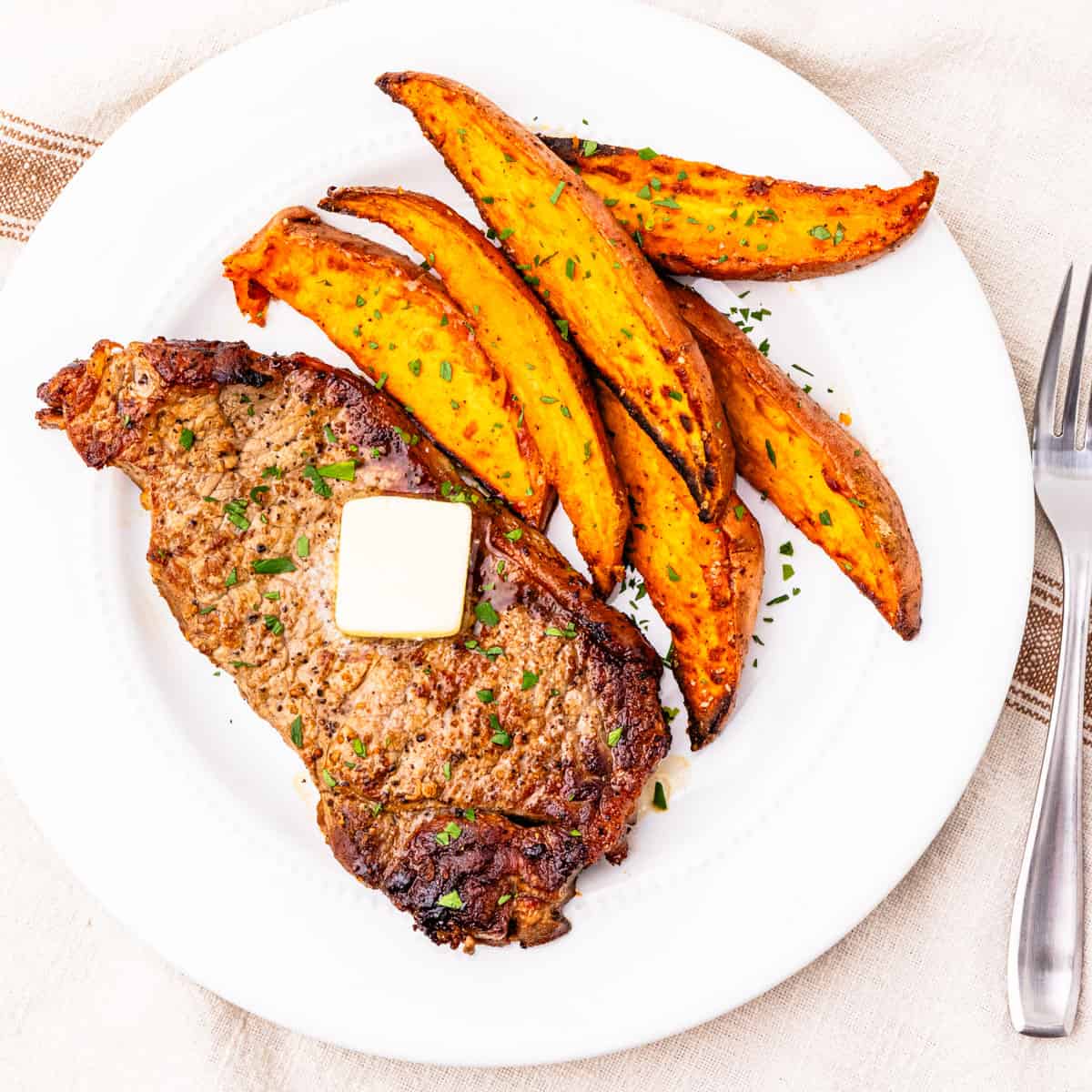 Seared steak served with sweet potato wedges.