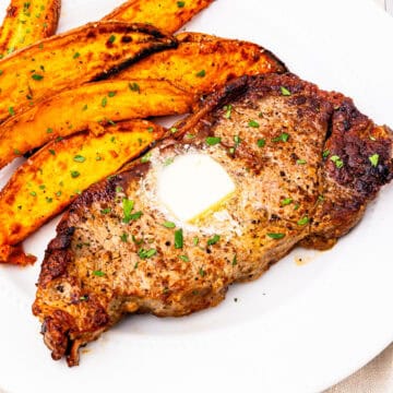 New York strip steak served on a plate with sweet potatoes.