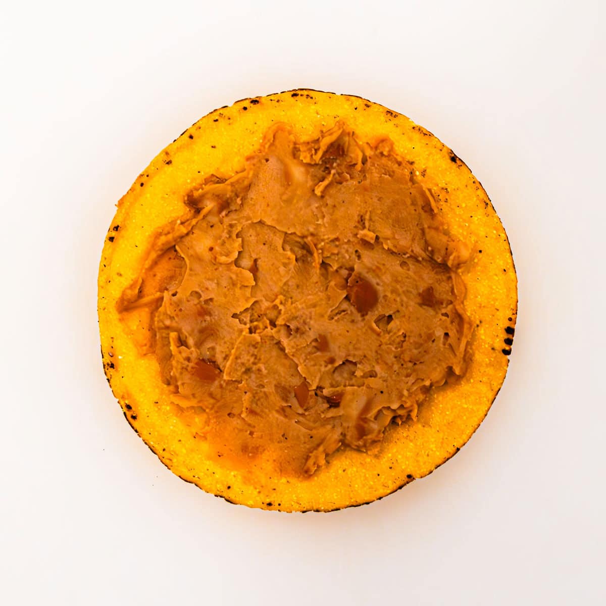 A tostada shell topped with a layer of refried beans. 