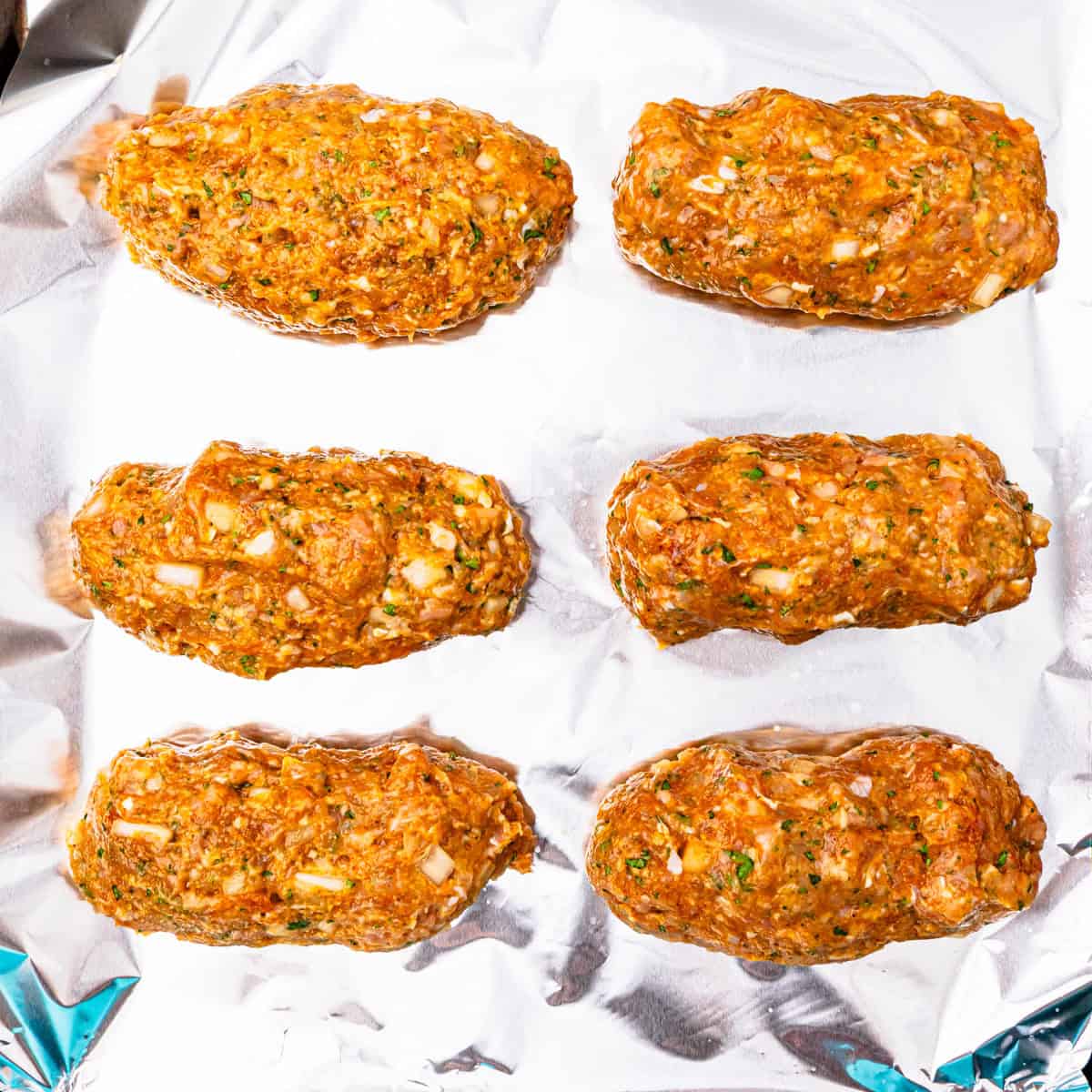 Chicken kofta being shaped on a sheet pan.