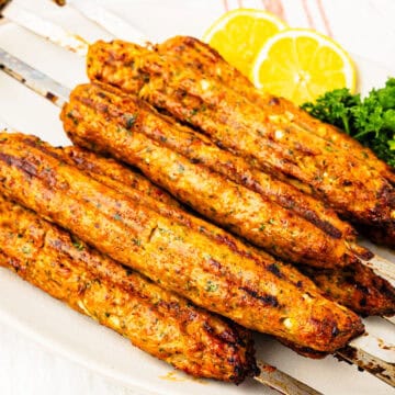 Grilled chicken kofta skewers on a platter.