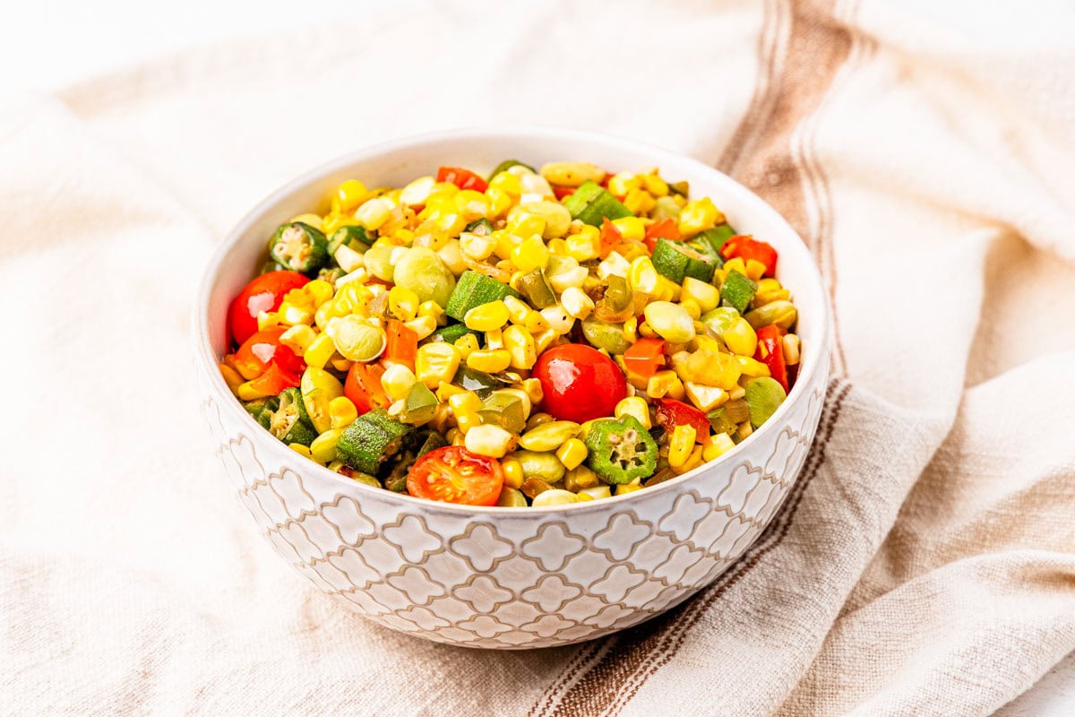 A bowl of succotash made with corn, okra, lima beans, and tomatoes.