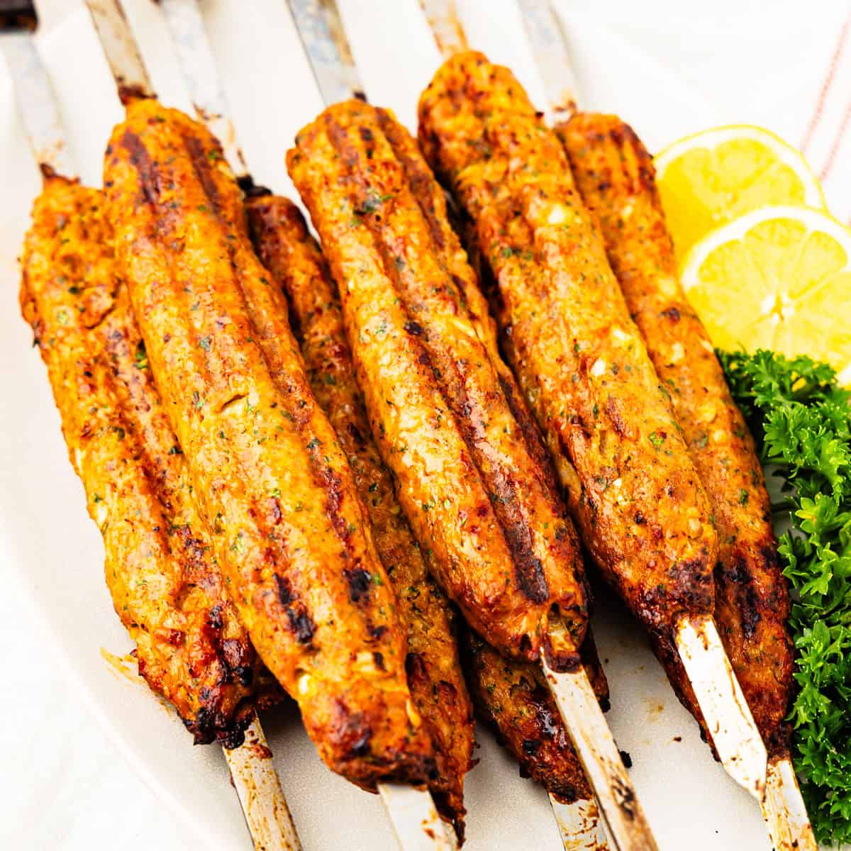 Grilled chicken kofta skewers on a platter. 