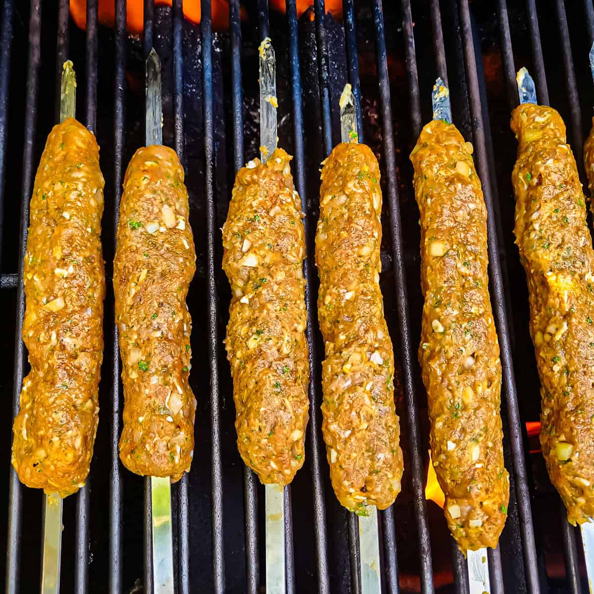 Chicken kofta kebabs cooking on a grill.