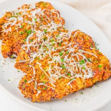 Parmesan crusted chicken cutlets served on a platter.