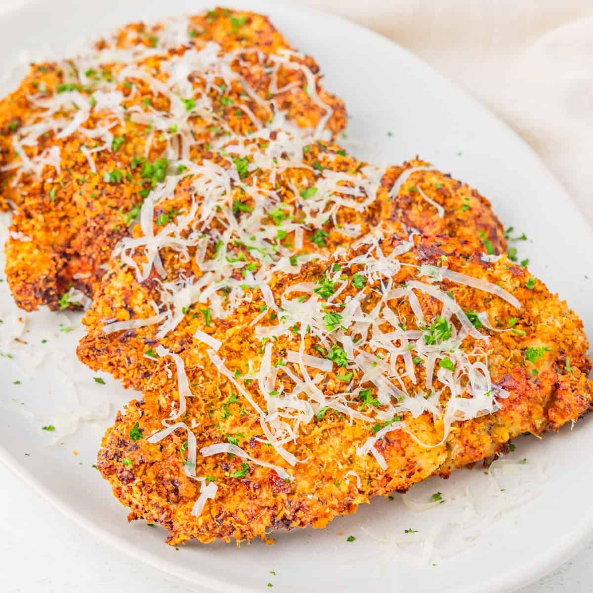 Parmesan crusted chicken cutlets served on a platter.