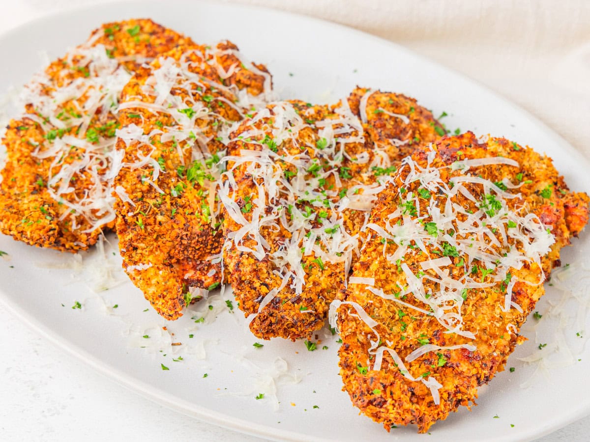 Parmesan crusted chicken cutlets served on a platter.