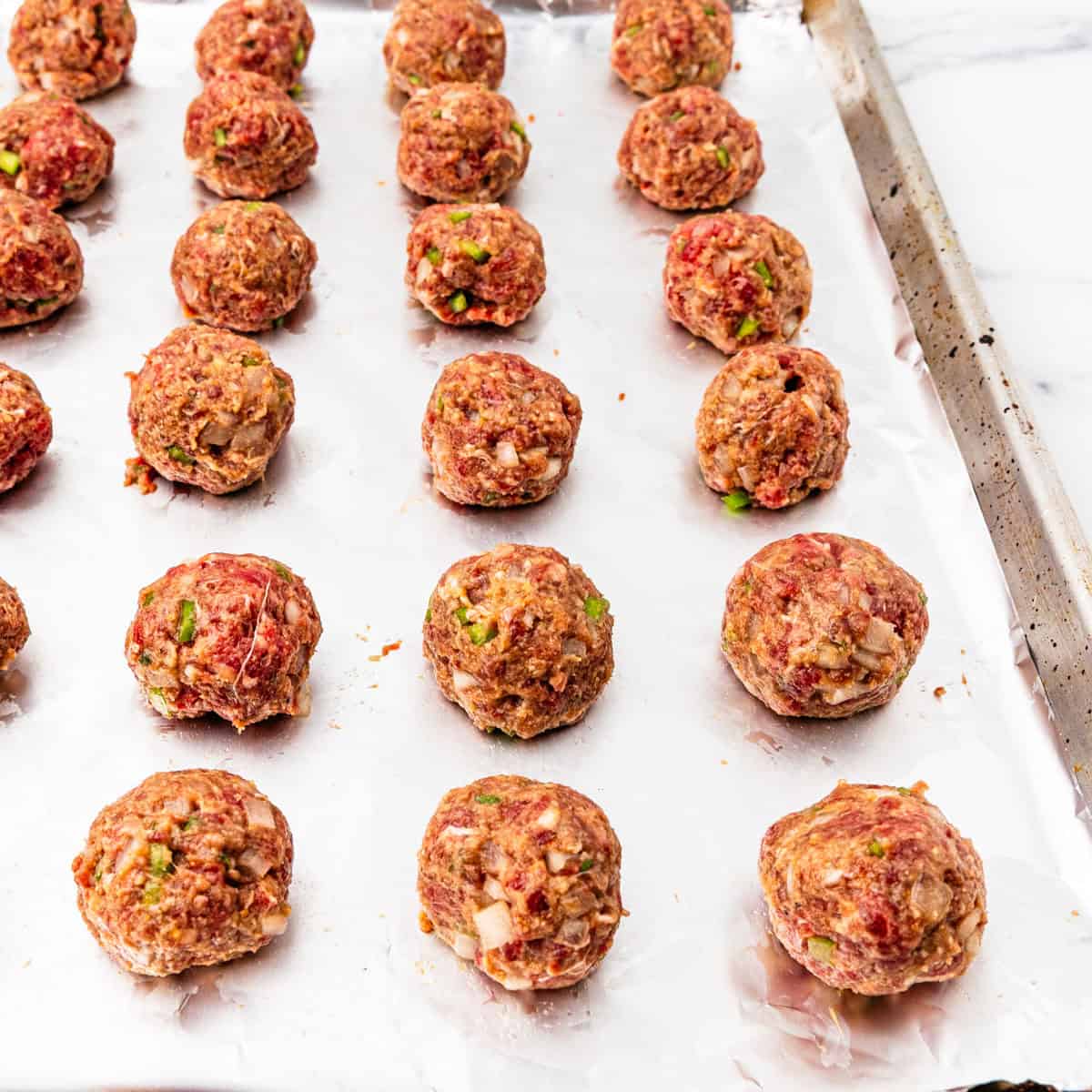 Uncooked meatballs on a baking sheet.