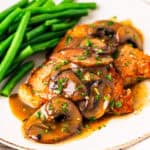 Pork chop marsala served on a plate with steamed green beans.