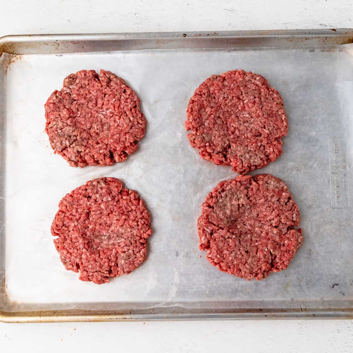Hamburger patties on a sheet pan.