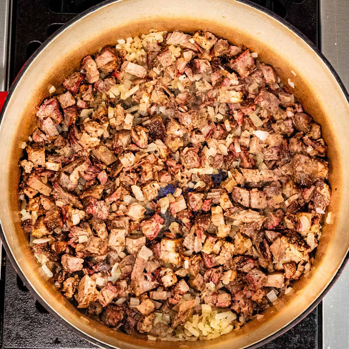 Chopped brisket and onion in a pot.