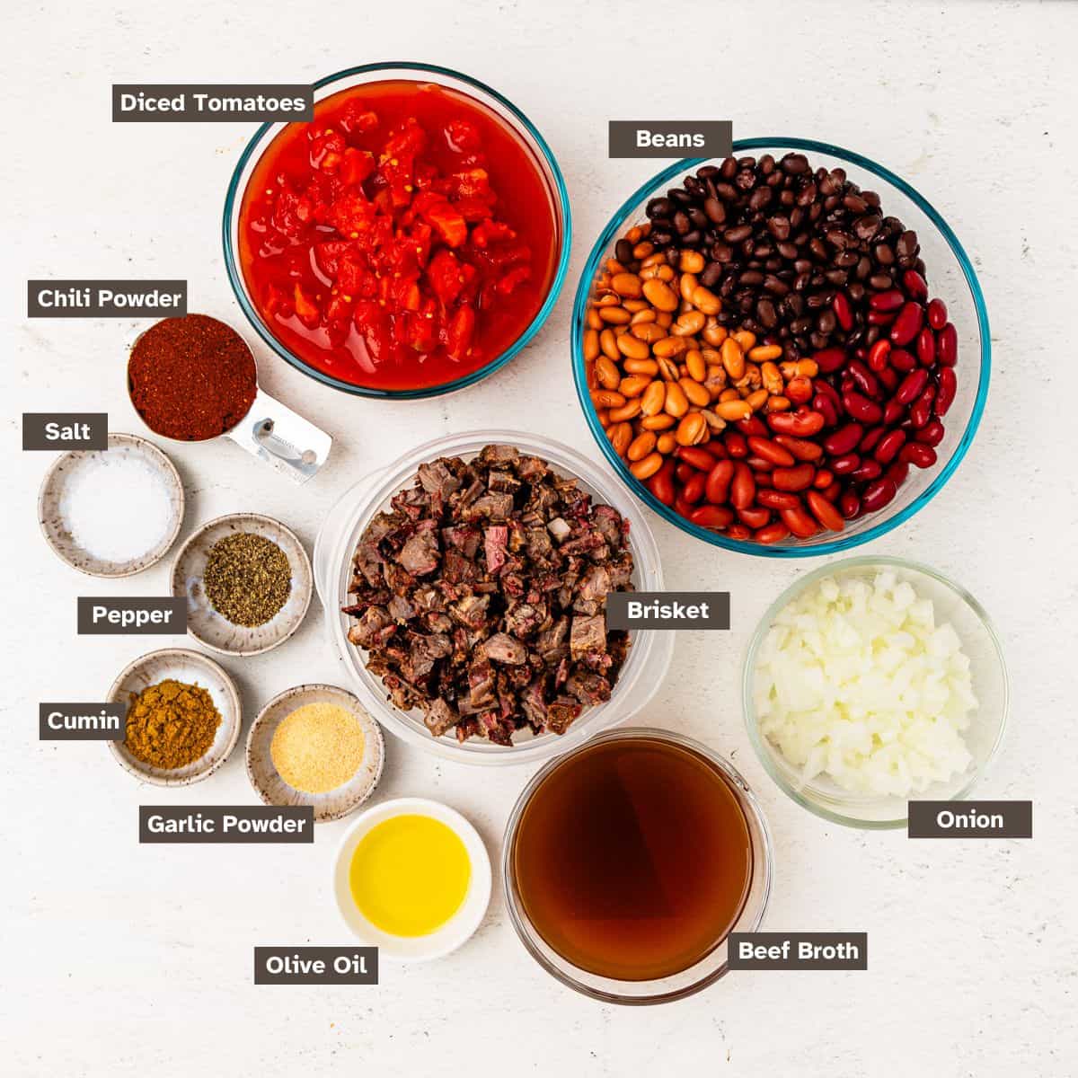 Ingredients for brisket chili arranged on a countertop in individual bowls.