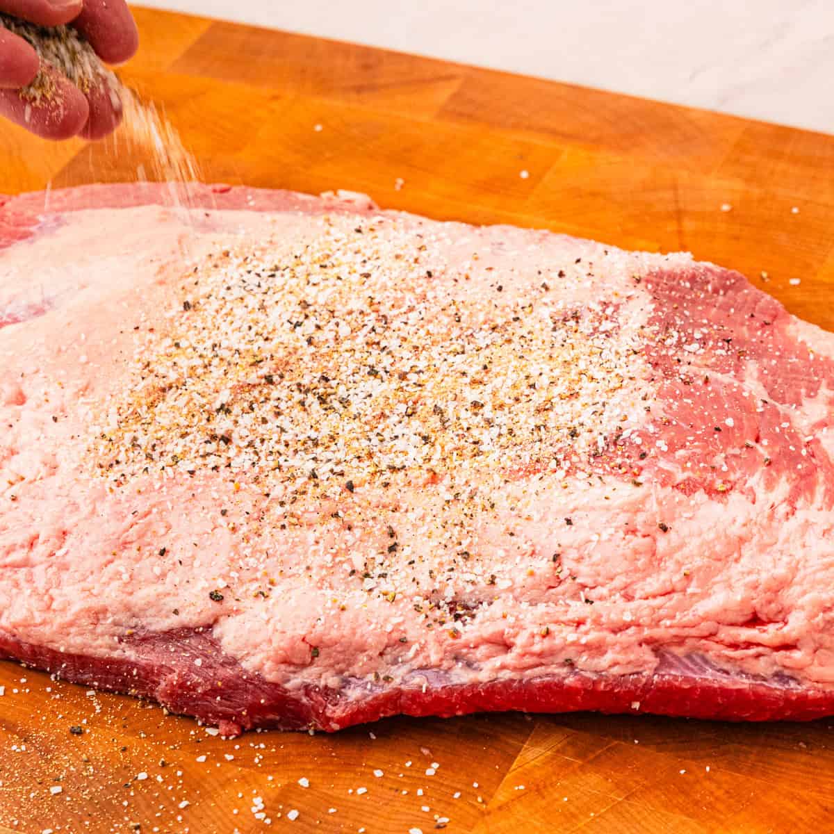 Seasoning a brisket with Texas rub.