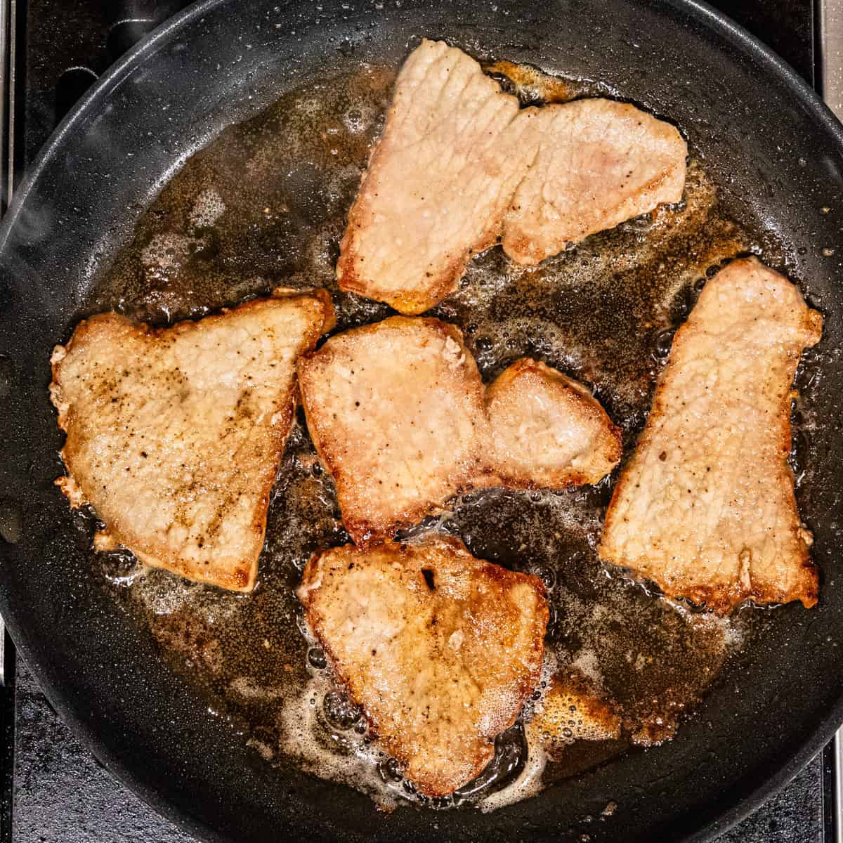 Seared veal cutlets in a skillet.