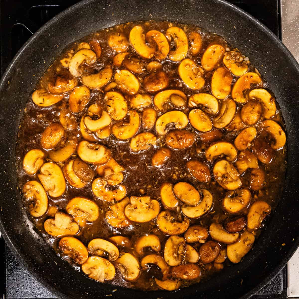 Marsala sauce and mushrooms in a skillet.