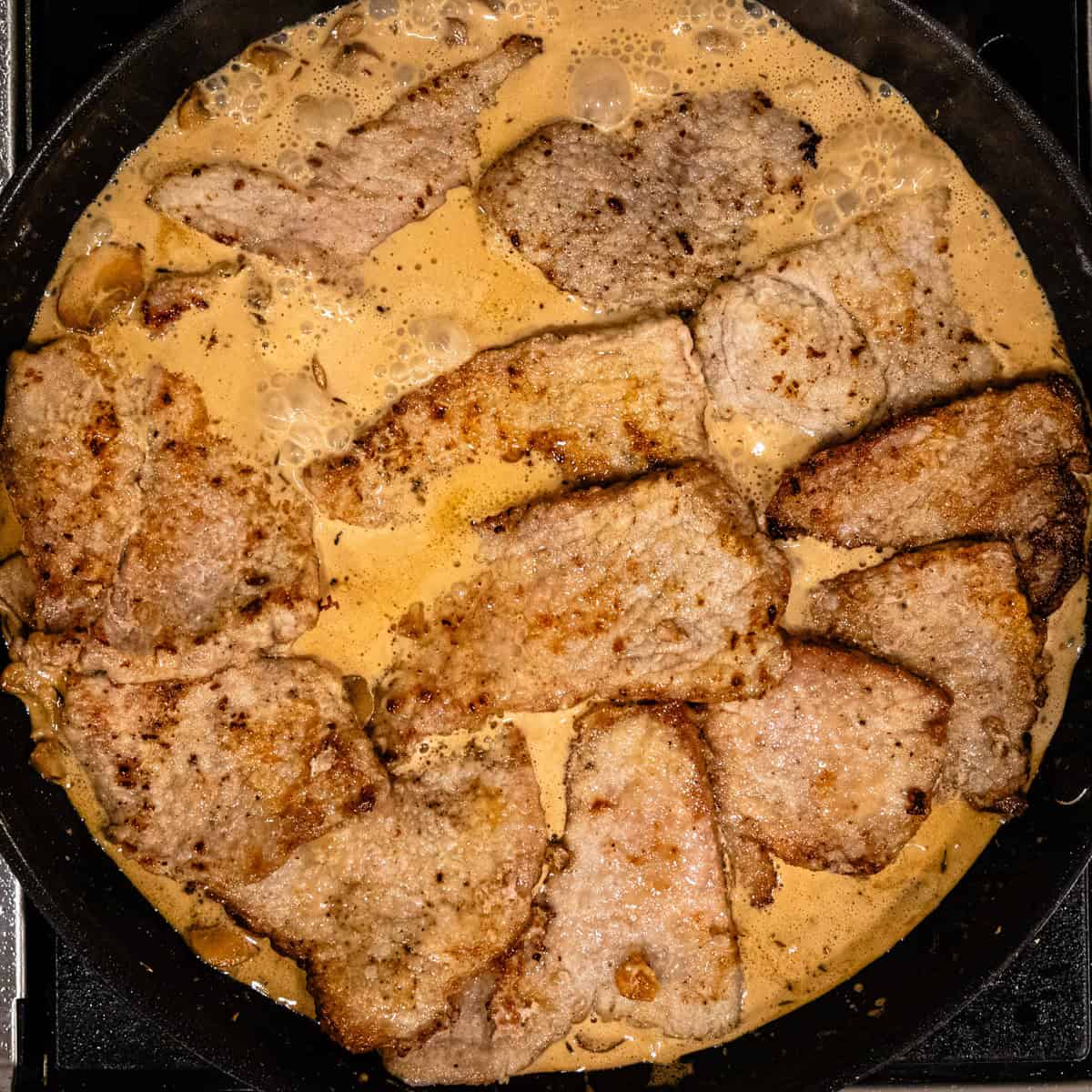 Veal marsala cooking in a skillet.