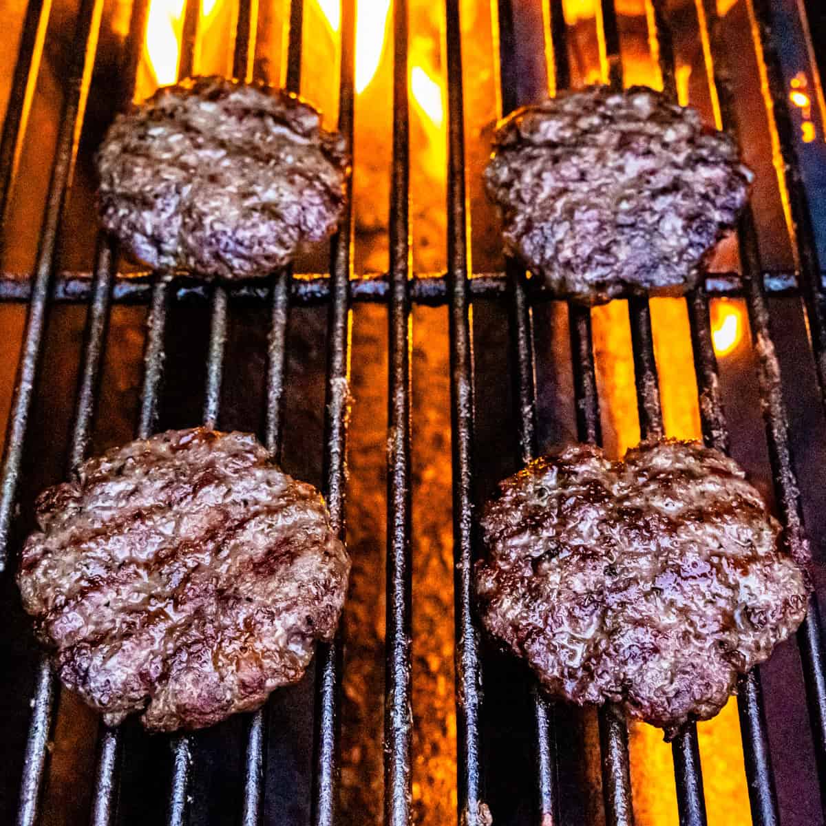 Cooked lamb burger patties on a grill.