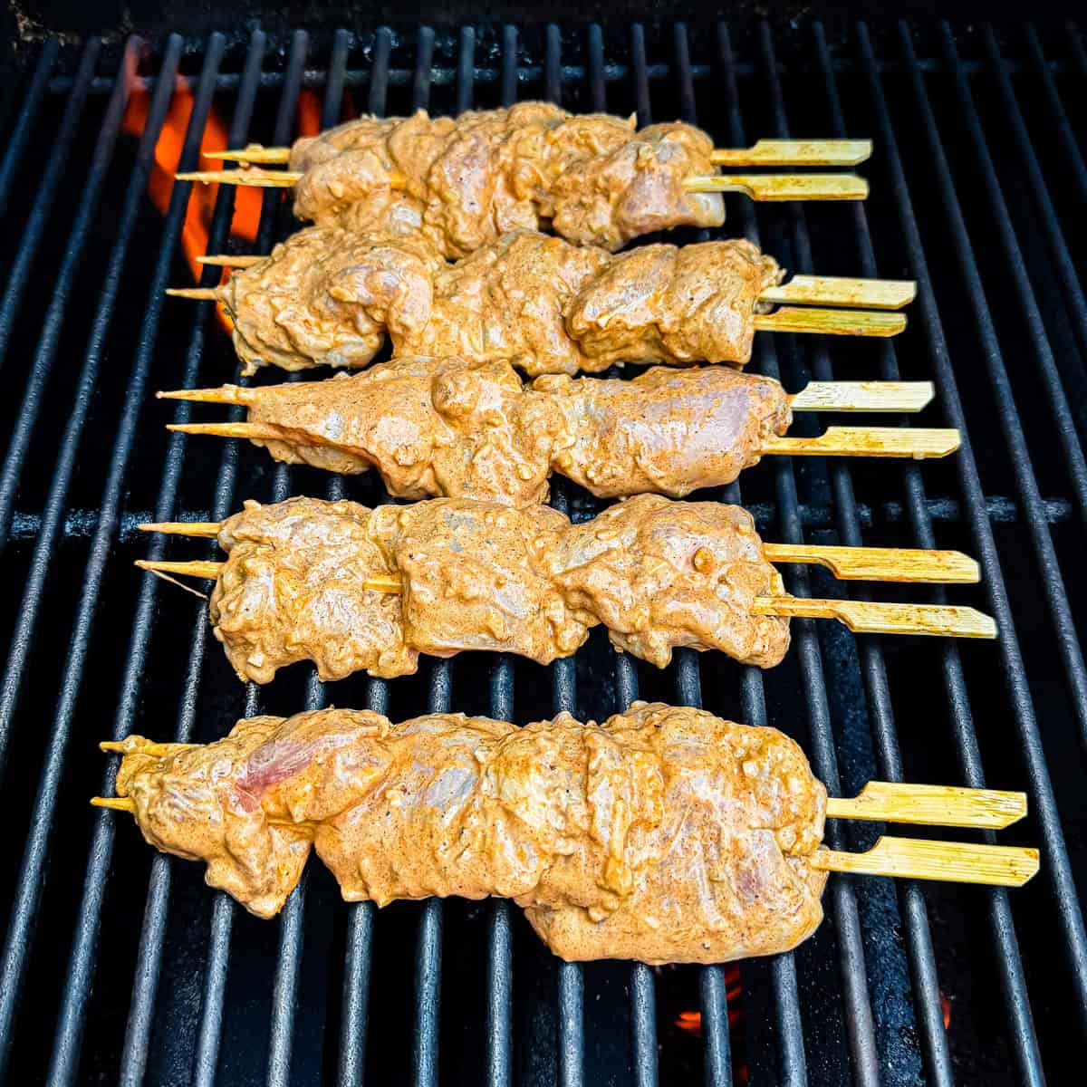 Chicken kabobs cooking on a grill.