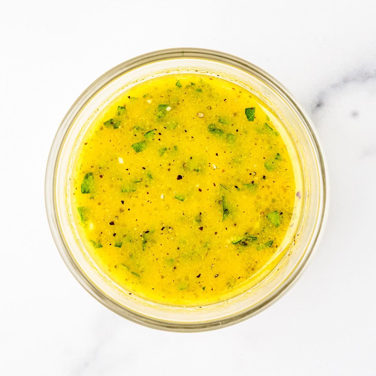 A small mixing bowl of lemon and herb vinaigrette dressing.