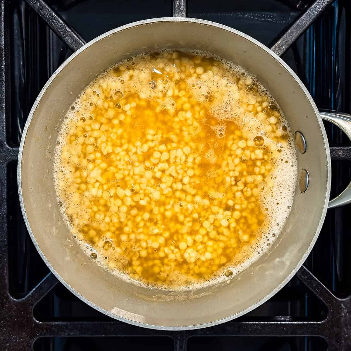 Couscous cooking in a pot with chicken stock.