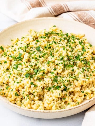 A bowl of lemon and herb couscous on a countertop.