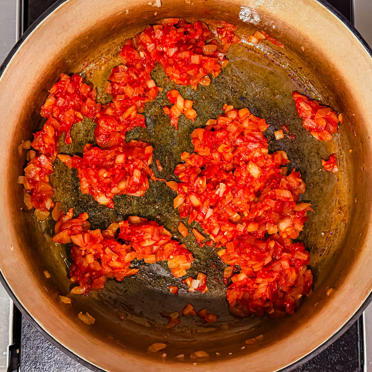 Onions, garlic, and tomato paste cooking in a large Dutch oven.