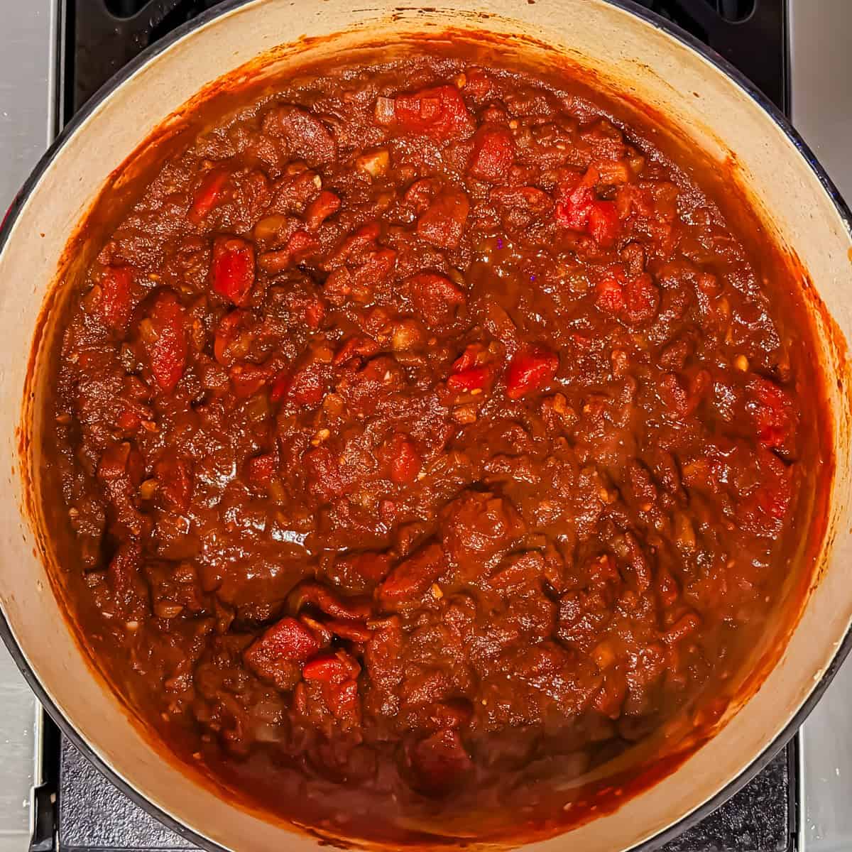 Tomatoes and chili spices in a large Dutch oven.