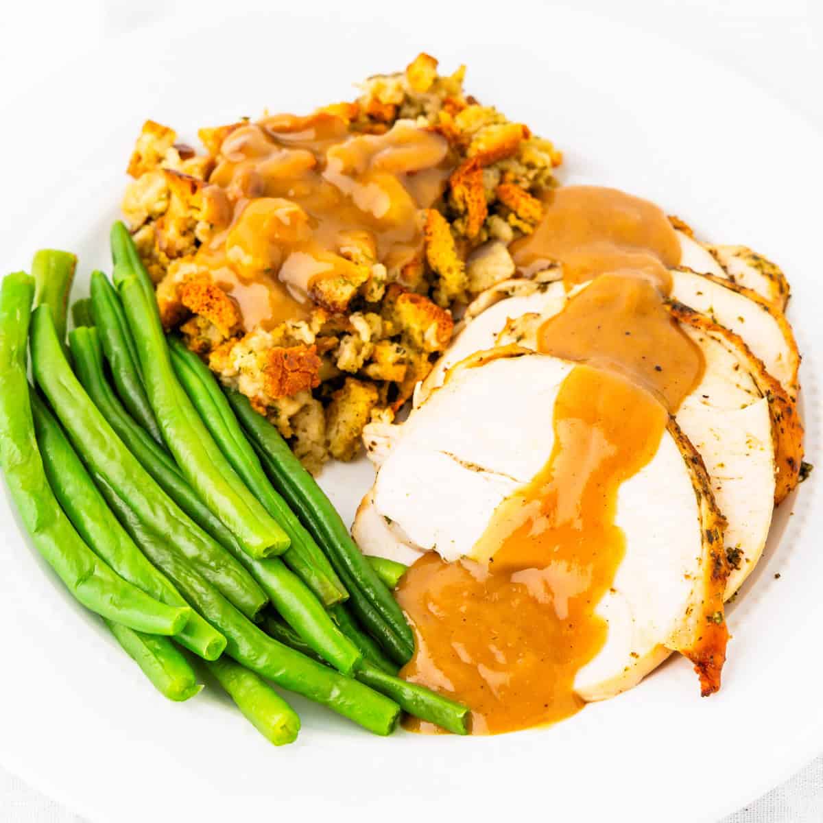 Roasted turkey breast and gravy served with stuffing and green beans.